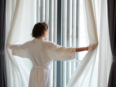 Woman in Bathrobe Opening Curtains